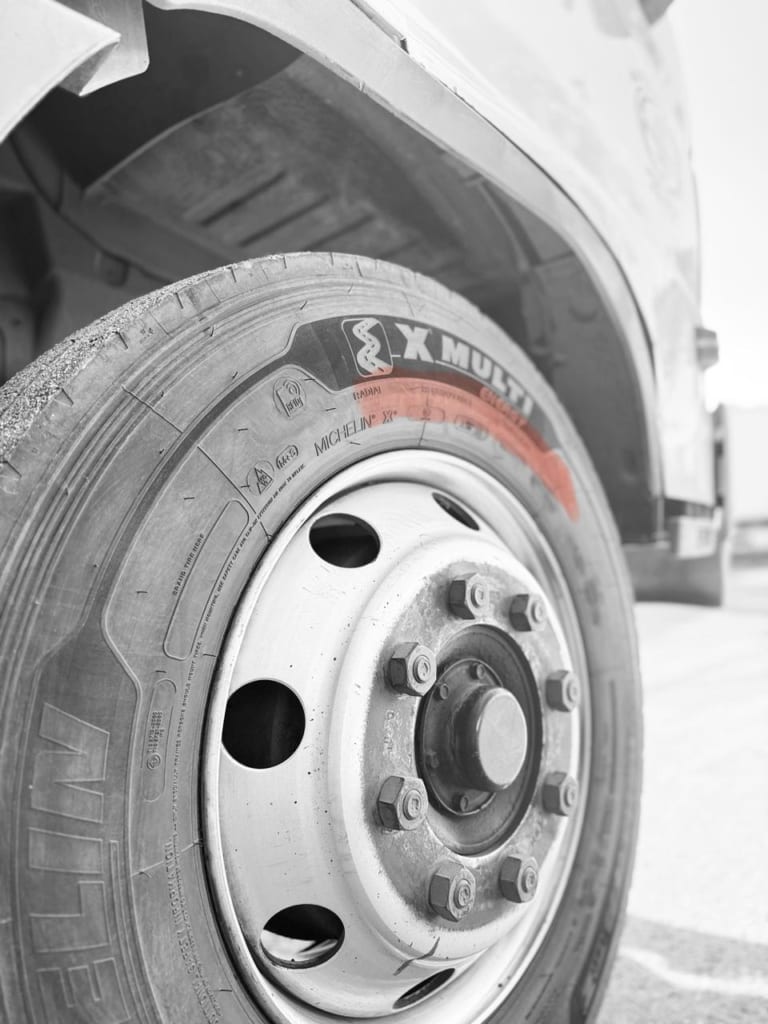 Close-up of a Michelin X Multi steer axle truck tire showing sidewall markings and heavy-duty wheel assembly.