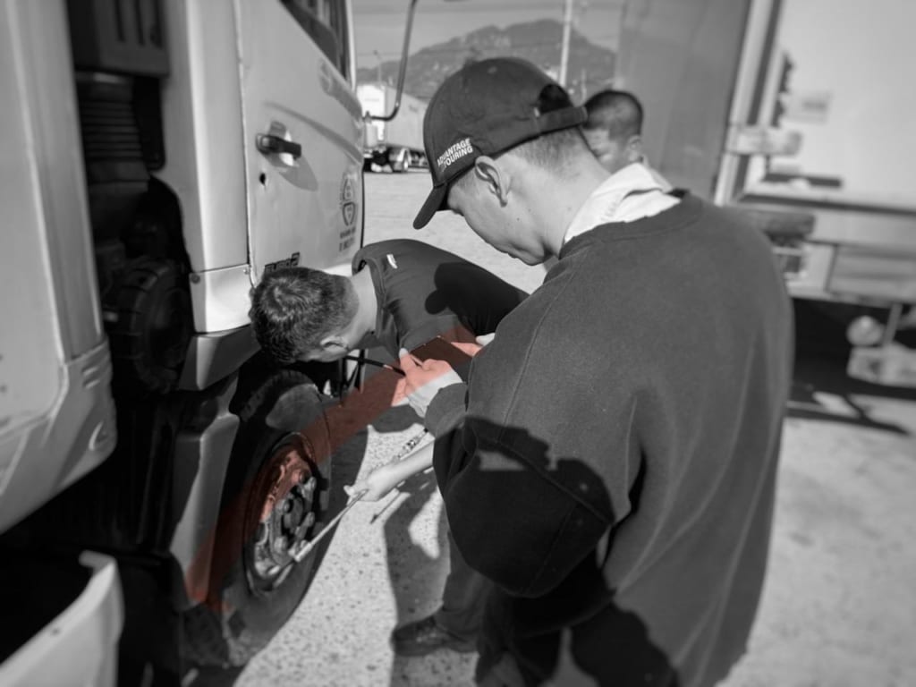 Fleet technician measuring truck tire tread depth using a digital gauge during tire inspection
