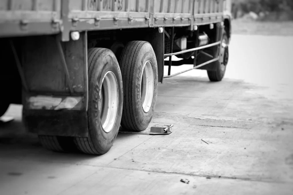 Close-up of a commercial heavy-duty truck tire parked on a portable wheel load scale to measure axle weight distribution for a precise tire inflation pressure calibration.