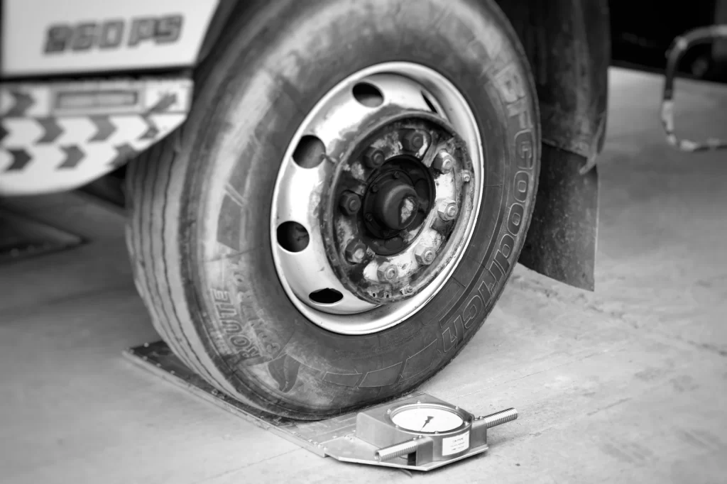 Close-up of a front steer axle truck tire on a portable mechanical wheel load scale, measuring individual wheel weight to calculate accurate steer tire cold inflation pressure.