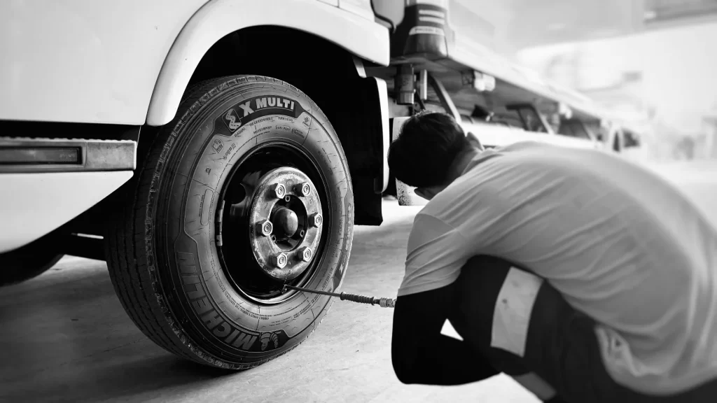 A fleet technician performing a routine cold inflation pressure check on a commercial truck steer tire.