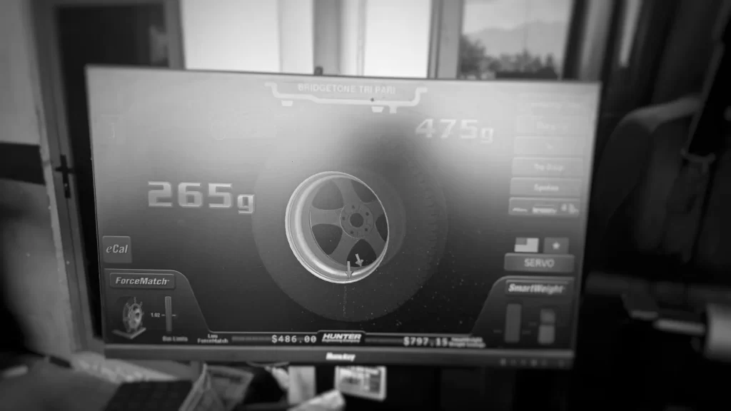 A Hunter wheel balancer monitor displaying required wheel weights of 265 grams and 475 grams for balancing a commercial truck tire assembly.